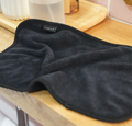 A soft black after-sex towel on a wooden nightstand, ready for Post-Intimacy clean-up.